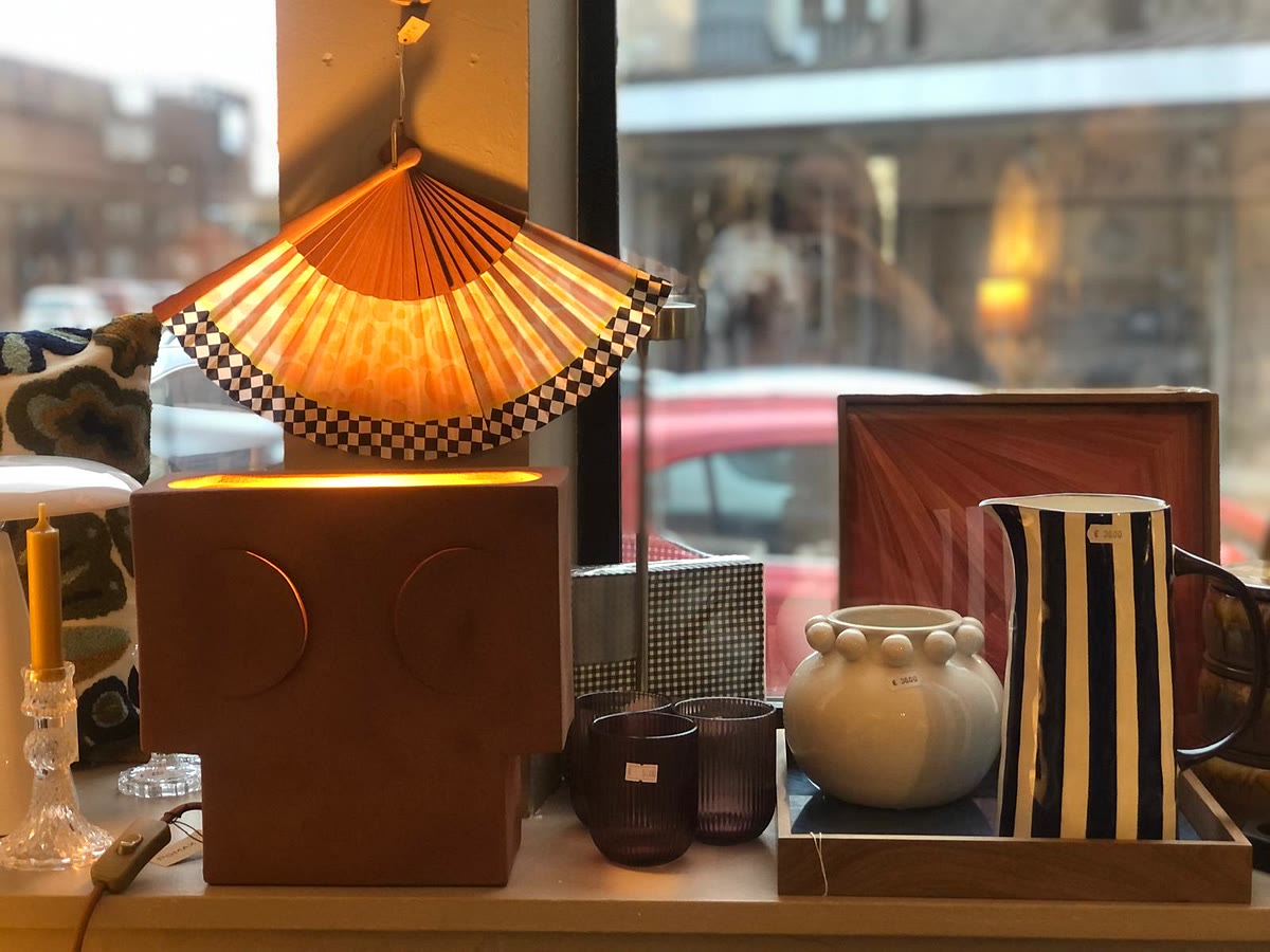 De etalage van de winkel: waaierlamp, gestreepte kan, vazen en dienblad